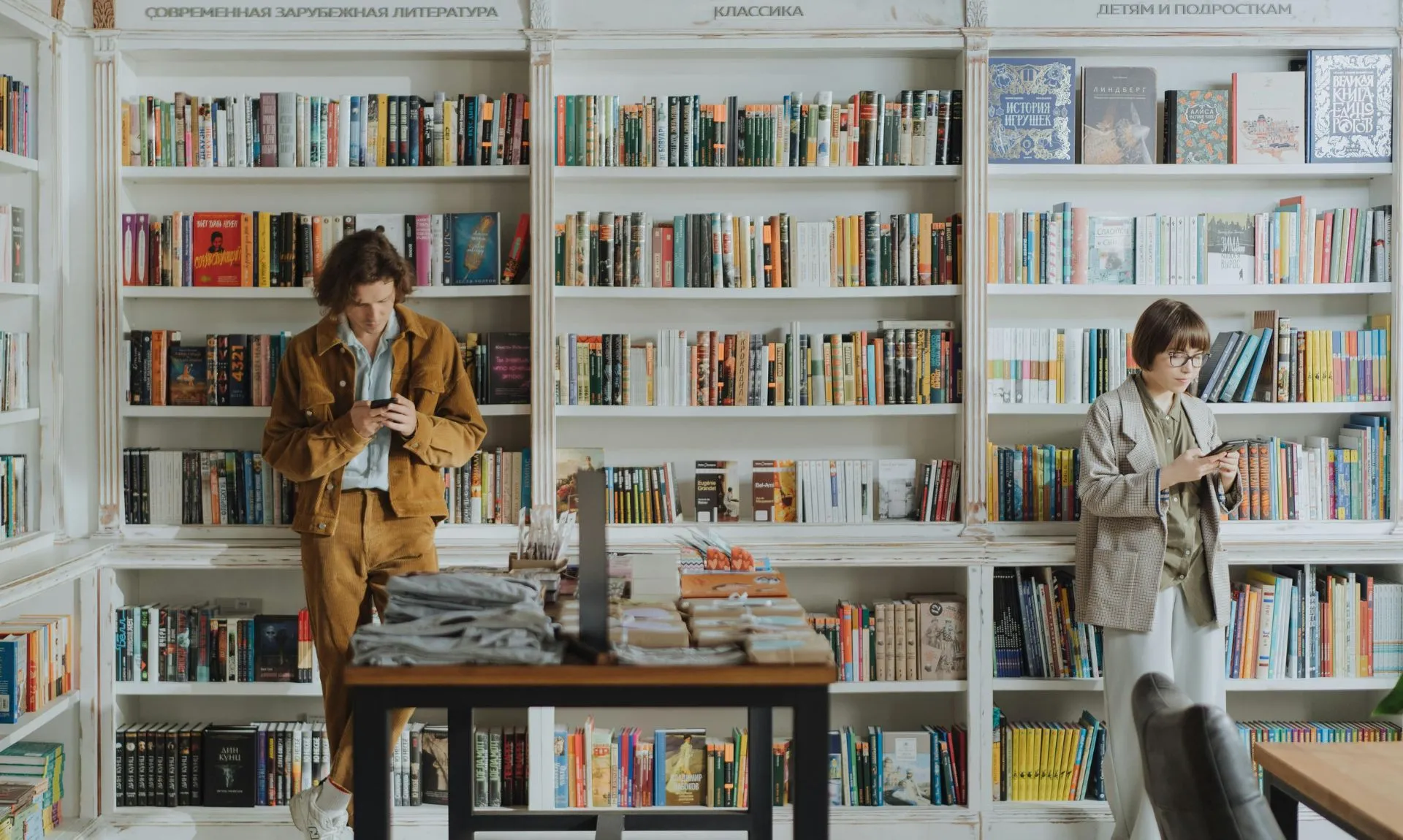 a girl and a boy in a library exploring contemporary books