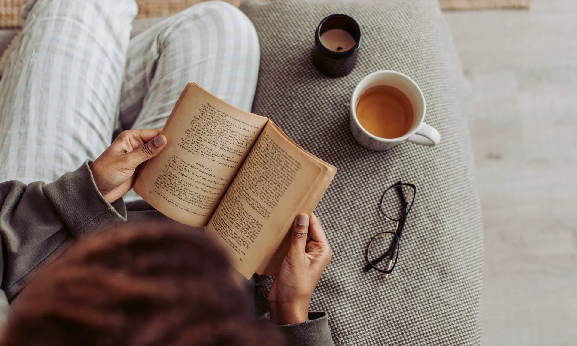 a girl reading book with a cup of tea