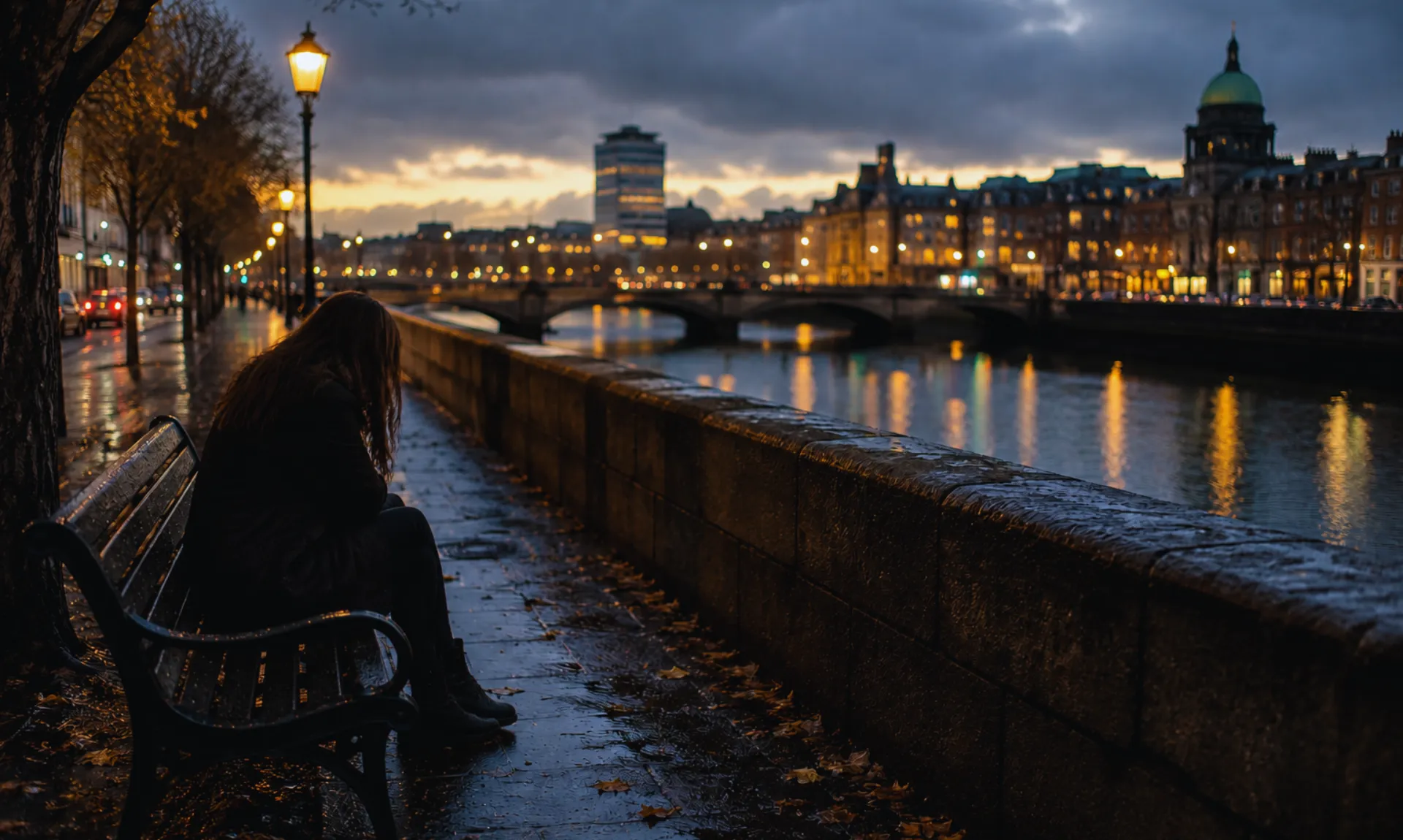 A solitary woman sits alone on a riverside bench at dusk, gazing across a rain-soaked cityscape as streetlights reflect on wet pavement, capturing themes of loneliness, longing, and emotional despair.