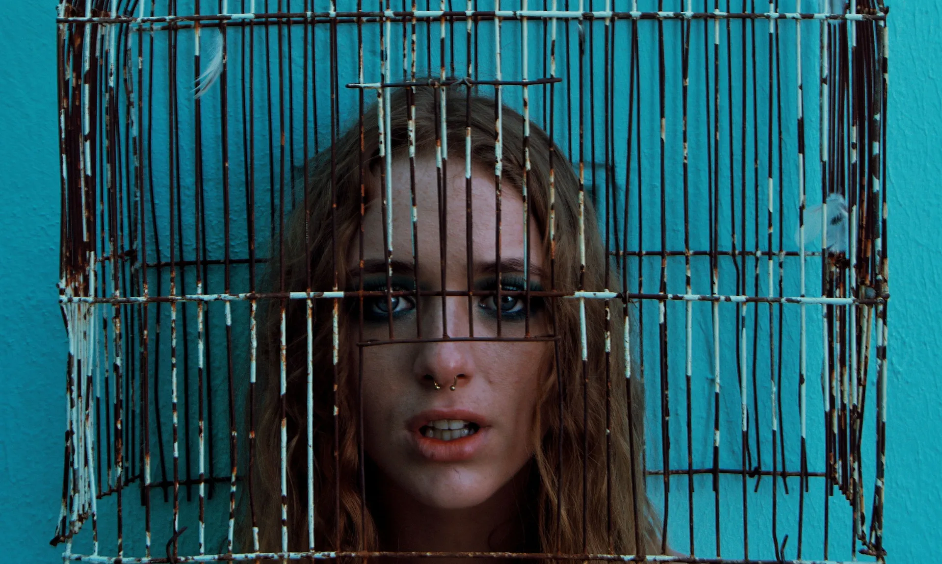 a girl trapped in a rusty bird cage