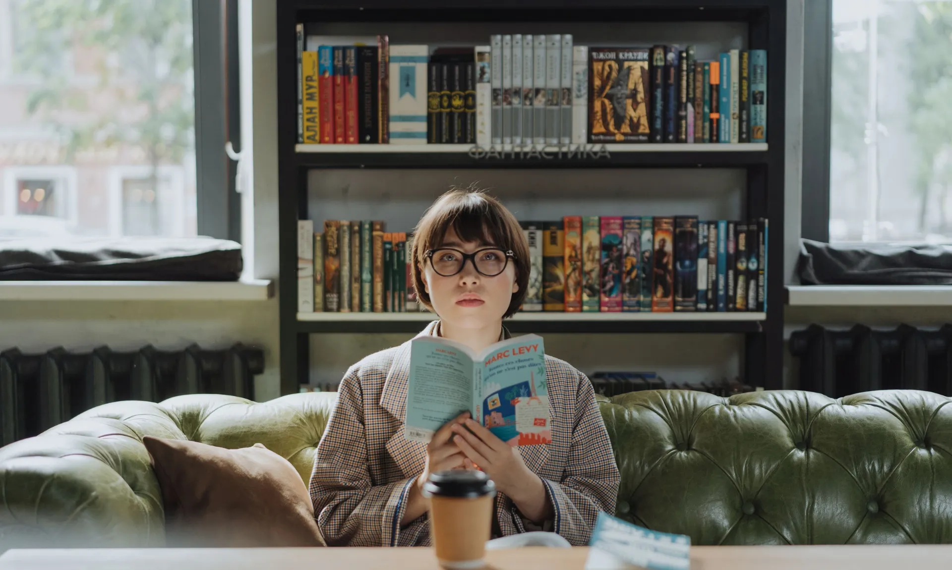 a girl sitting on couch with a book in hand